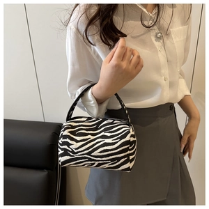 Close-up of zebra print mini pillow bag with black leather handle and fabric texture