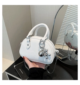 Detailed shot of white lychee leather mini bag with silver chain and balloon dog charm