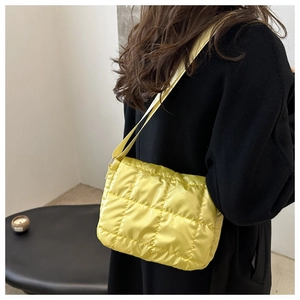 Detail of bright yellow quilted puffer bag worn by model over a dark stylish coat