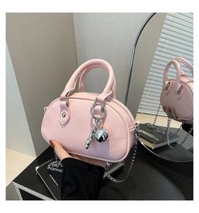 Close-up of pink lychee leather bag with dual round handles and silver chain detail