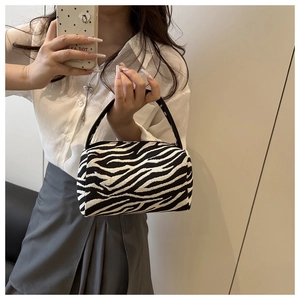 Mirror selfie showing the compact zebra print barrel bag with black leather handles