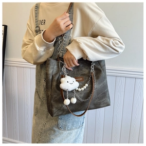 Close-up of vintage canvas tote with leather label, pearl chain, and cloud charm detail