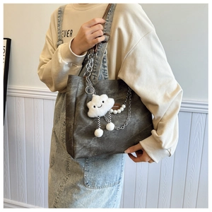 Detail of dark grey canvas tote bag with pearl chain and plush cloud charm accessory