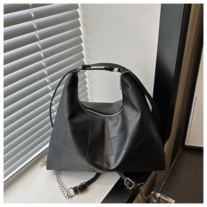 Detail of black patchwork leather hobo bag with silver chain and matte grain texture