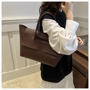 Close-up of a brown leather tote bag showing smooth texture and large flap design