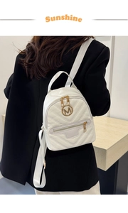 Detailed view of a white quilted mini backpack with a gold M logo on a female model