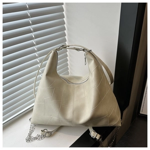 Detail of off-white hobo bag showing irregular stitching and silver zipper closure