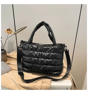 Détail d'un sac cabas noir matelassé avec finition brillante et bandoulière réglable