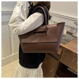 Fashionable dark brown PU leather tote bag shown on model in a cozy indoor setting