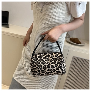 Detailed close-up of a leopard print pillow bag with slim black handles and fabric texture