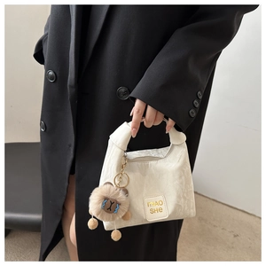Close-up of white marble textured handbag with Miaoshe logo and brown plush animal charm