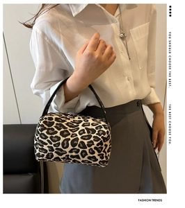 Close-up of leopard print mini box bag featuring black leather handle and fabric texture