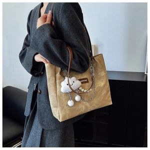 Detail of a ginger corduroy tote bag with silver chain, pearls and cloud plush charm