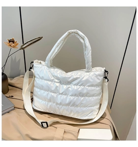 Détail d'un sac cabas matelassé blanc brillant avec poignées rembourrées et bandoulière
