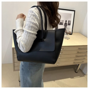 Vista dettagliata di una grande borsa tote in pelle nera opaca indossata da una modella