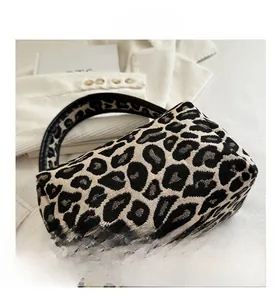 Detail shot of leopard jacquard mini handbag with black leather handle on white knit
