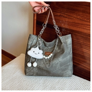 Close-up of vintage canvas tote bag with chain strap, leather logo and plush charm