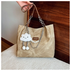 Detail of khaki canvas tote bag with chain strap, leather logo tag and cloud charm