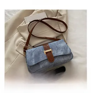 Détail du sac sous le bras en denim bleu clair avec bandoulière marron et boucle