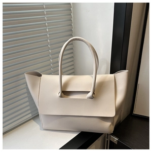 Detail of minimalist cream leather tote bag featuring a unique handle closure design