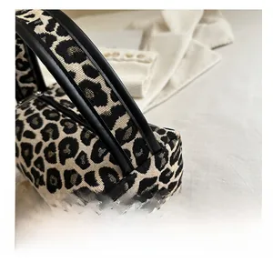 Close-up of leopard jacquard fabric and black leather handles on a mini barrel bag