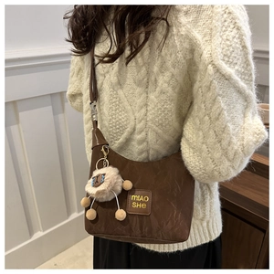 Detalle de bolso de hombro marrón con etiqueta MIAO SHE y colgante de oveja de felpa