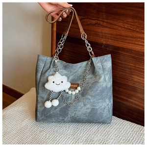 Detail of blue denim tote bag with chain strap and cute white cloud plush pendant