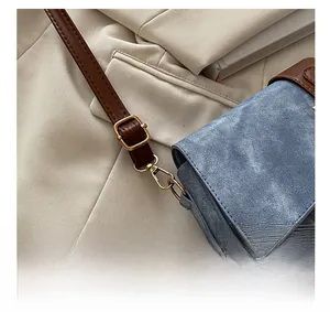 Détail du sac en denim avec bandoulière en cuir marron et boucles dorées brillantes
