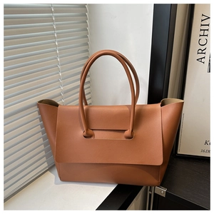 Close-up of caramel brown leather tote bag with unique flap design and cylindrical handle