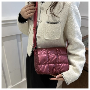 Close-up of metallic pink quilted crossbody bag with adjustable nylon shoulder strap