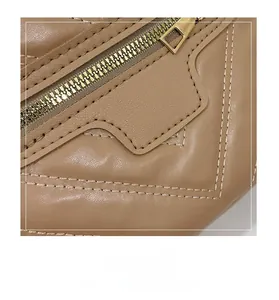 Detail of khaki leather bag showing premium texture with gold zipper and reinforced stitching