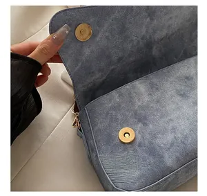 Détail montrant le fermoir magnétique et la texture denim du sac à bandoulière bleu