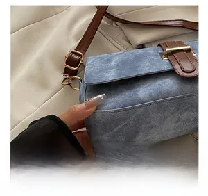 Détail du sac sous les aisselles en denim bleu avec garniture en cuir brun et boucle d'or