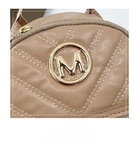 Detail of khaki quilted leather bag with golden M logo and metallic zipper puller
