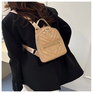 Detail view of khaki quilted mini backpack with gold letter M logo on model