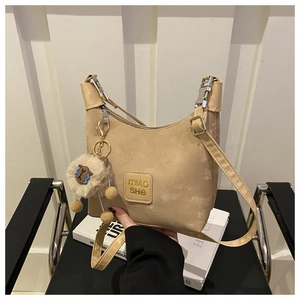 Close-up of beige suede shoulder bag with leather logo tag and cute sheep charm