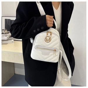 Detailed view of white quilted mini backpack with golden M logo on a female model