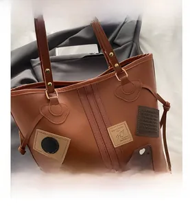 Detail view of caramel brown tote bag with fashion lucky patches and side drawstring