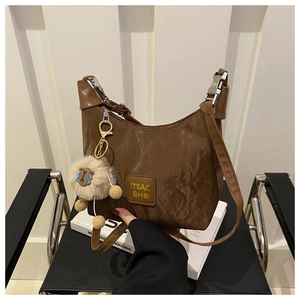 Detail of dark brown crinkled nylon hobo bag with logo patch and cute alpaca pendant