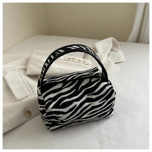 Detailed view of the zebra pattern handbag with curved top handle and secure zipper