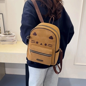 Detail view of the yellow cat-themed backpack with ears and embroidery worn by a model