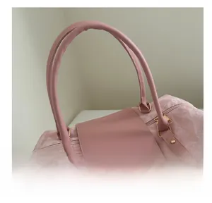 Close-up of the textured fabric and reinforced leather handle on a pink travel tote bag