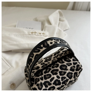 Detail of leopard print jacquard tote bag with black leather handle on white fabric