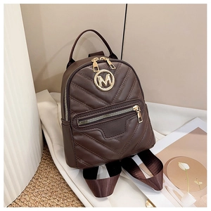 Detail of dark brown mini backpack featuring V-shaped quilting and a gold M logo plaque