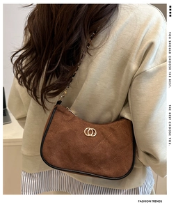 Detail view of brown suede half-moon underarm bag with quilted diamond pattern and gold buckle