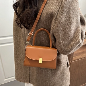 Sac à main classique en cuir marron caramel avec fermoir doré sur un manteau en laine