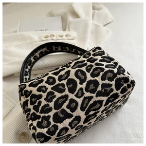 Close-up of stylish leopard print fabric mini handbag on a textured corduroy background