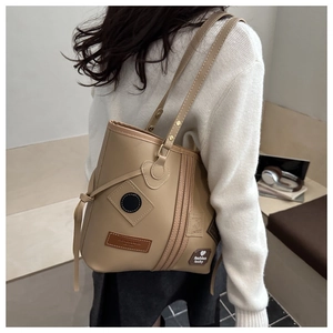 Detail of a beige PU leather tote bag showing patch decorations and shoulder carry fit