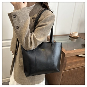 Détail d'un sac cabas en cuir noir avec texture grainée et lettrage doré élégant