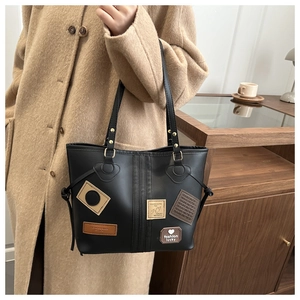 Close-up of black matte leather tote bag with fashion patches and golden metal hardware